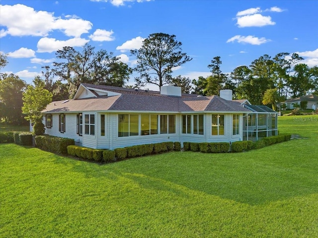 rear view of property featuring a lanai, a yard, and a chimney