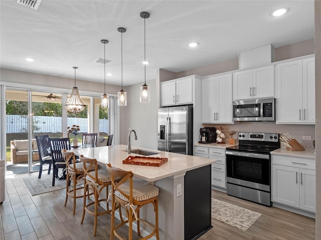 kitchen with a sink, stainless steel appliances, visible vents, and light wood-style flooring