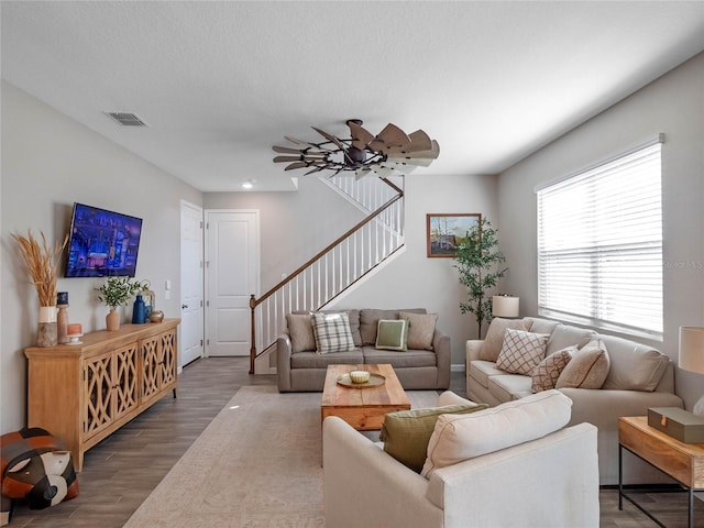 living room with stairway, wood finished floors, visible vents, and a textured ceiling