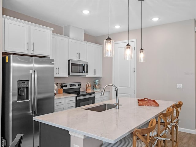 kitchen with a sink, stainless steel appliances, a kitchen bar, and white cabinets