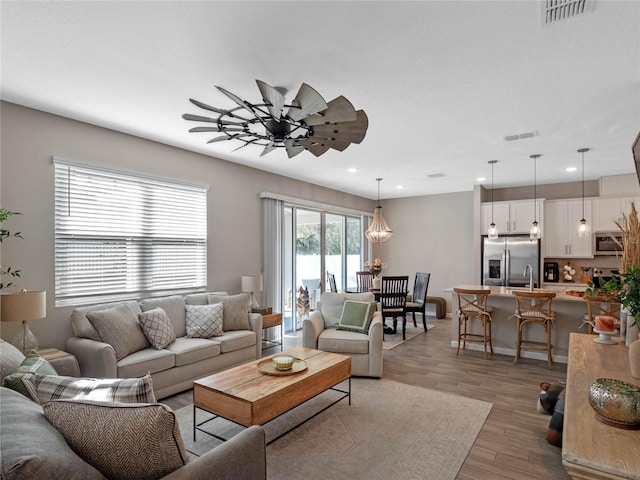 living room featuring light wood finished floors, visible vents, recessed lighting, and ceiling fan