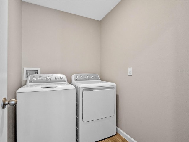 clothes washing area featuring laundry area, light wood-type flooring, baseboards, and washer and clothes dryer