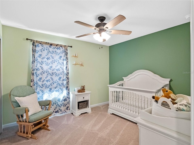 bedroom featuring a nursery area, a ceiling fan, baseboards, and carpet floors