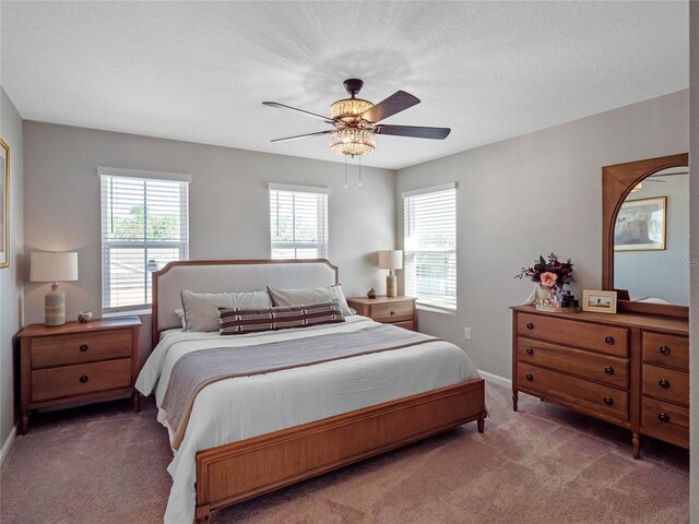 bedroom featuring baseboards, multiple windows, a ceiling fan, and carpet