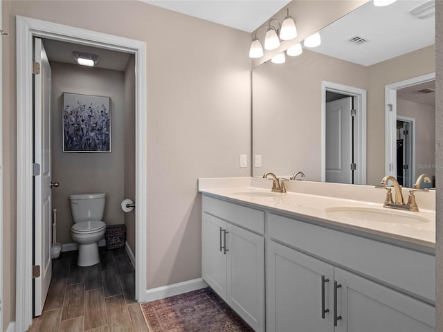 bathroom featuring visible vents, toilet, wood tiled floor, and a sink