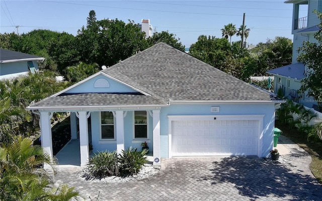 ranch-style home featuring decorative driveway, a garage, roof with shingles, and stucco siding