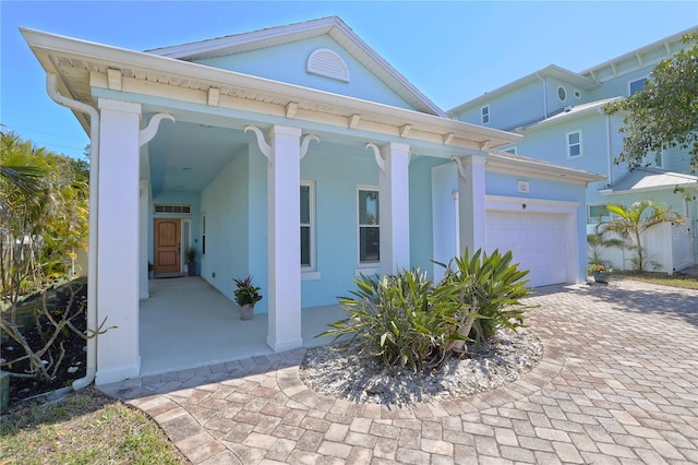 view of front of property with stucco siding, driveway, a porch, and an attached garage