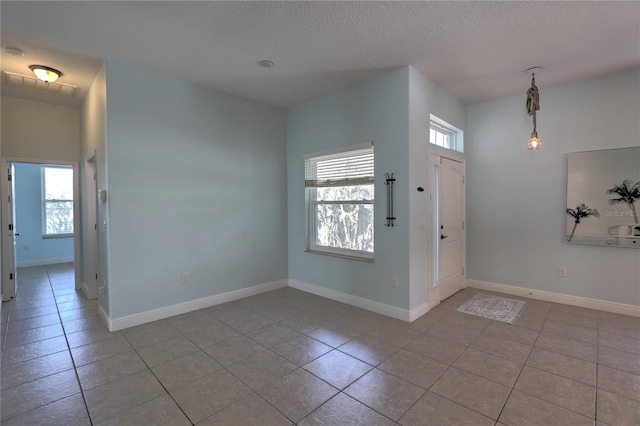 entrance foyer featuring tile patterned flooring, a textured ceiling, and baseboards