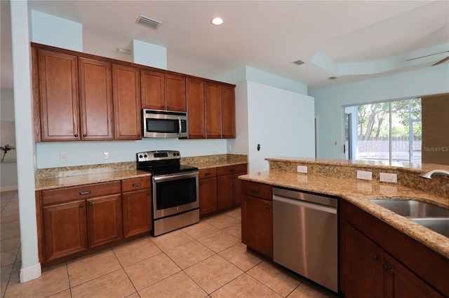 kitchen with light tile patterned floors, light stone countertops, visible vents, a sink, and stainless steel appliances