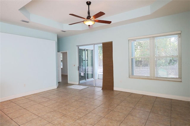 unfurnished room featuring a healthy amount of sunlight, baseboards, and a tray ceiling