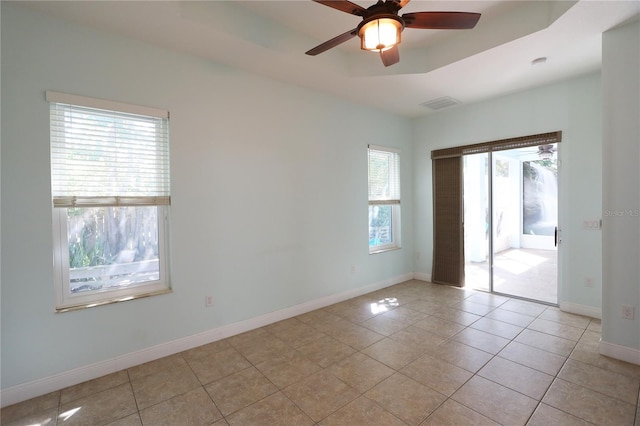 spare room featuring visible vents, ceiling fan, baseboards, and a tray ceiling