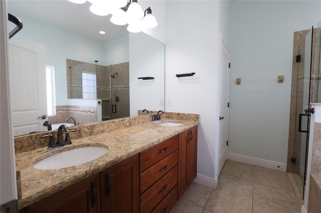 bathroom featuring a chandelier, a shower stall, double vanity, and a sink