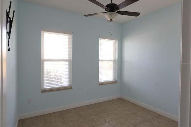 empty room with light tile patterned floors, a ceiling fan, and baseboards