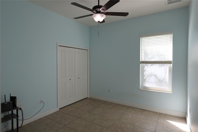 unfurnished bedroom with visible vents, a closet, tile patterned flooring, baseboards, and ceiling fan