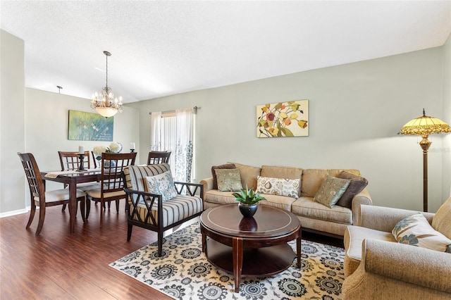 living room featuring an inviting chandelier, wood finished floors, baseboards, and a textured ceiling