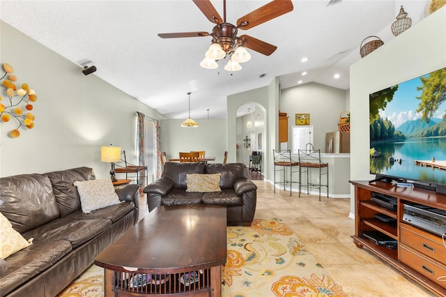 living area featuring baseboards, ceiling fan, lofted ceiling, arched walkways, and a textured ceiling