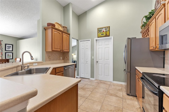 kitchen with a sink, backsplash, appliances with stainless steel finishes, light countertops, and light tile patterned floors