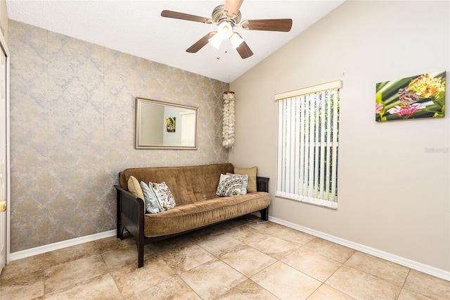 living area featuring baseboards, lofted ceiling, ceiling fan, and tile patterned flooring