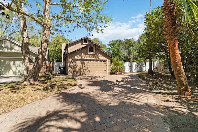 view of front of property featuring a garage, driveway, and fence