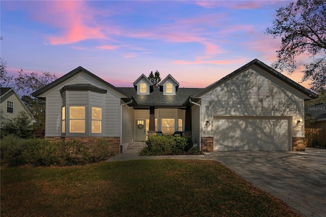 view of front facade featuring a garage, decorative driveway, stone siding, and a yard