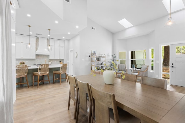 dining area with visible vents, high vaulted ceiling, a skylight, recessed lighting, and light wood-type flooring