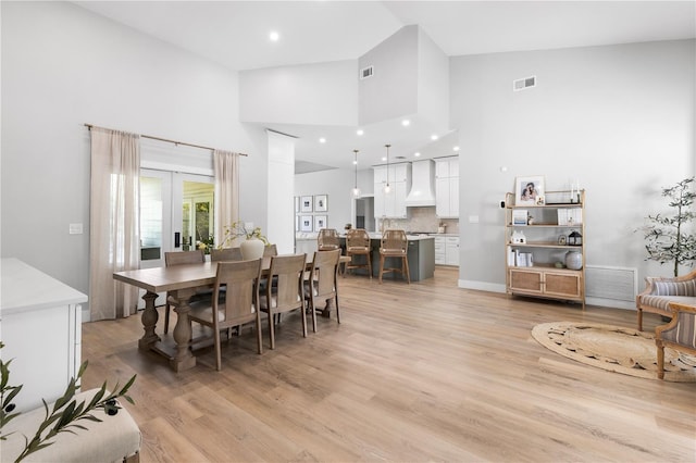 dining area featuring light wood-style flooring, recessed lighting, visible vents, and high vaulted ceiling