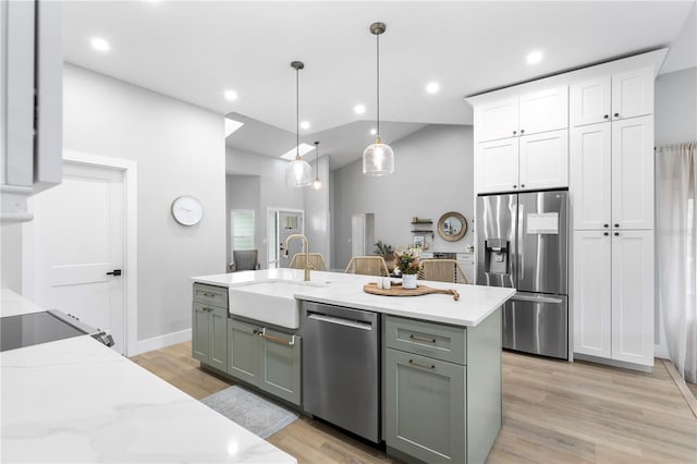 kitchen featuring light wood finished floors, a sink, hanging light fixtures, white cabinets, and appliances with stainless steel finishes