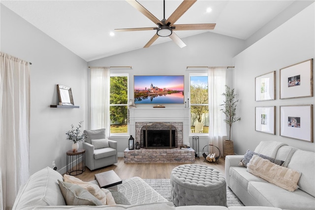 living area with plenty of natural light, a brick fireplace, wood finished floors, and vaulted ceiling