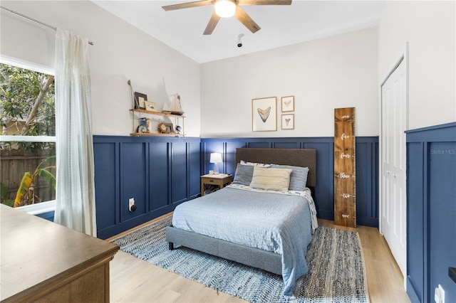 bedroom with a wainscoted wall, a decorative wall, and light wood finished floors