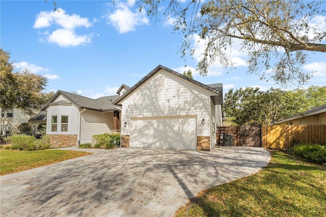 view of front facade featuring a front lawn, driveway, stone siding, fence, and a garage