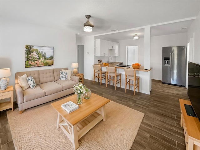 living room with dark wood-style floors, visible vents, and ceiling fan