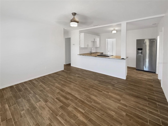 kitchen with dark wood finished floors, a peninsula, a sink, high end refrigerator, and white cabinetry