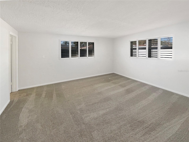 carpeted empty room featuring baseboards and a textured ceiling