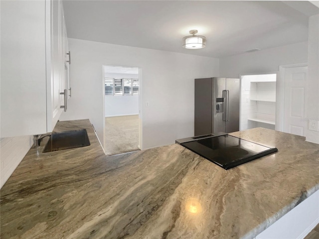 kitchen featuring cooktop, white cabinets, and high end fridge