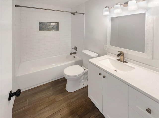 full bath with toilet, wood finished floors, vanity, and shower / tub combination