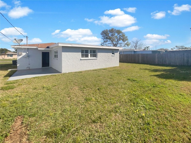 back of house with a patio, a yard, fence, and stucco siding