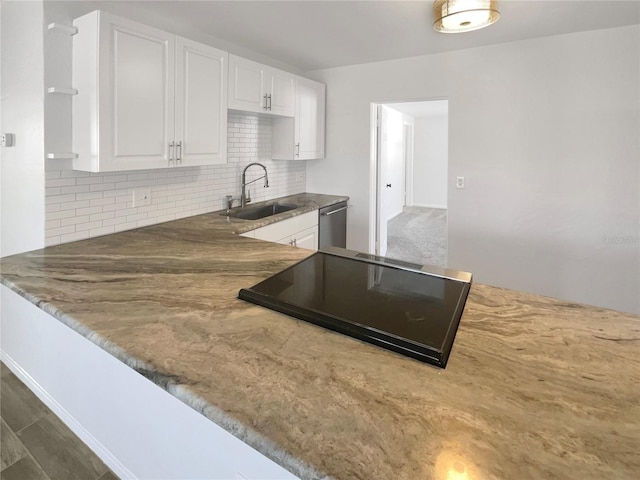 kitchen featuring tasteful backsplash, black electric stovetop, dishwasher, white cabinets, and a sink