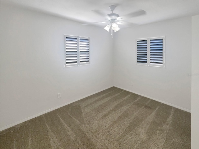 empty room with a ceiling fan, baseboards, and dark carpet