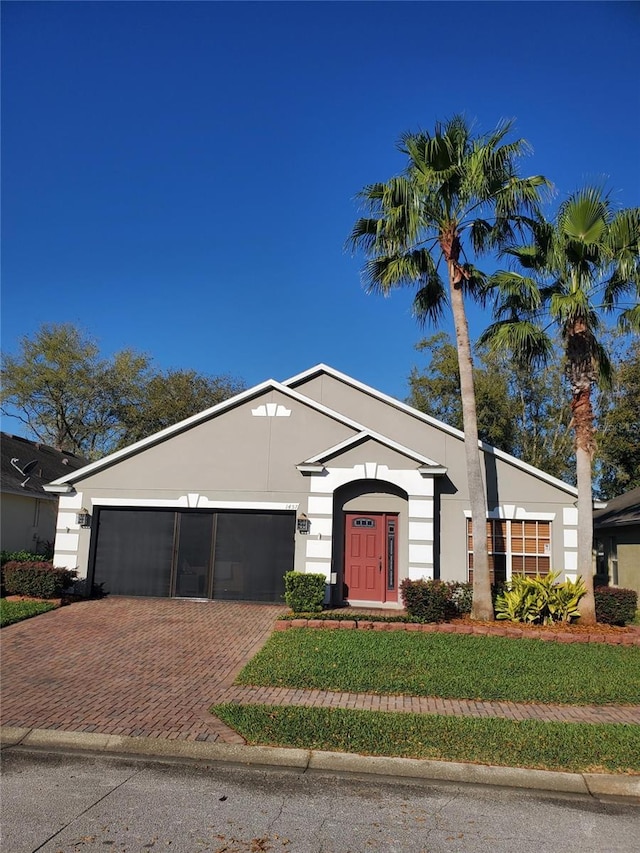 view of front of property featuring decorative driveway, a garage, a front lawn, and stucco siding