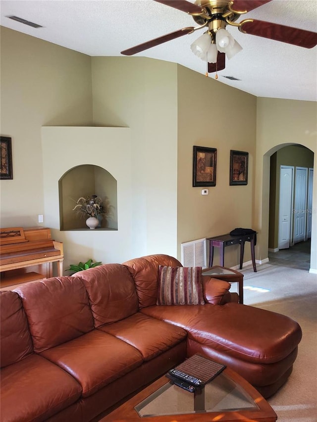 living area featuring visible vents, light carpet, arched walkways, lofted ceiling, and ceiling fan