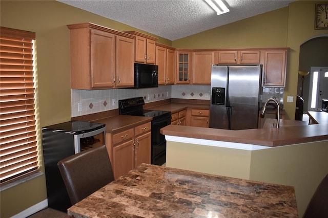 kitchen featuring lofted ceiling, black appliances, glass insert cabinets, a textured ceiling, and backsplash