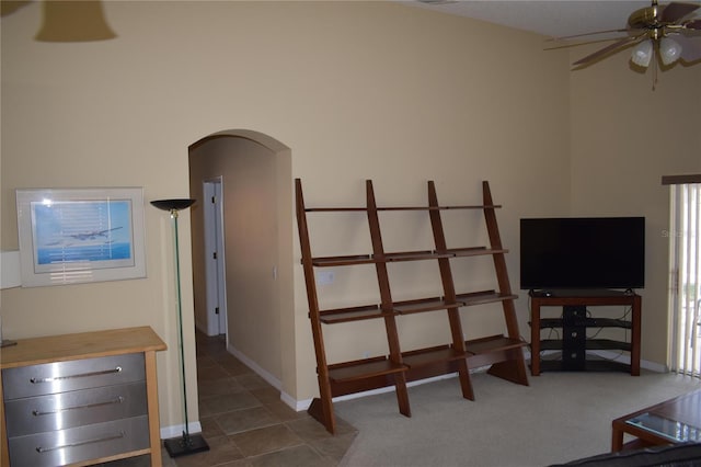 carpeted living room with arched walkways, baseboards, and a ceiling fan