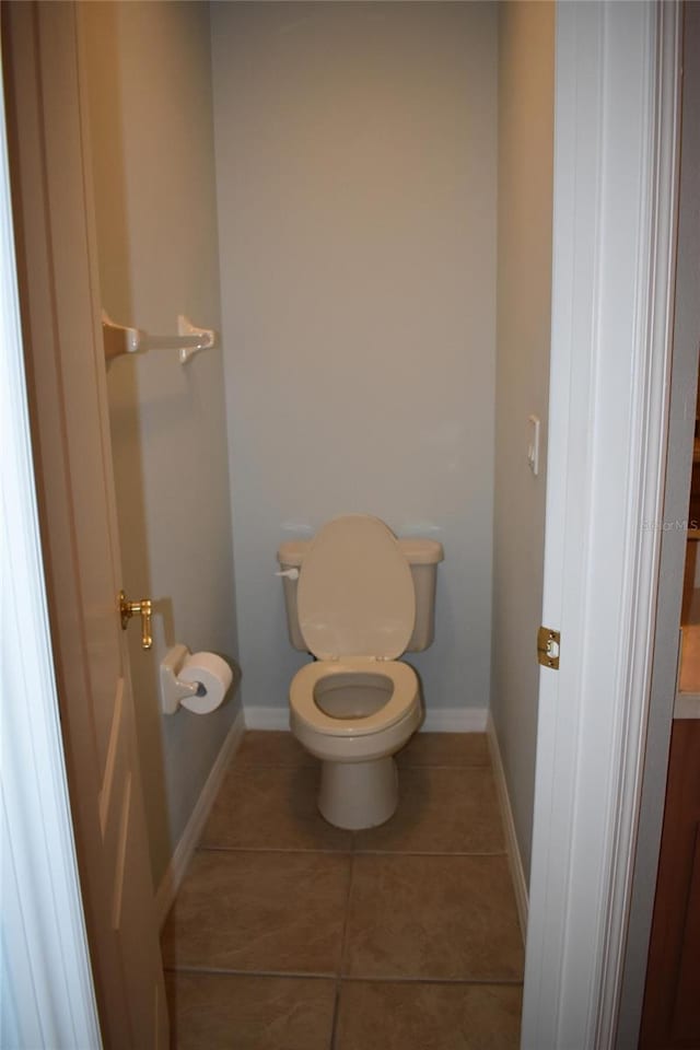 bathroom featuring tile patterned flooring, toilet, and baseboards