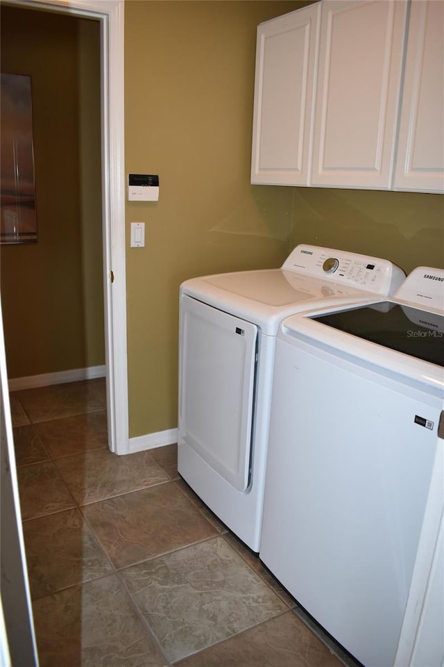 clothes washing area with tile patterned floors, baseboards, cabinet space, and independent washer and dryer