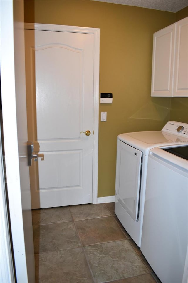 clothes washing area with cabinet space, independent washer and dryer, and baseboards