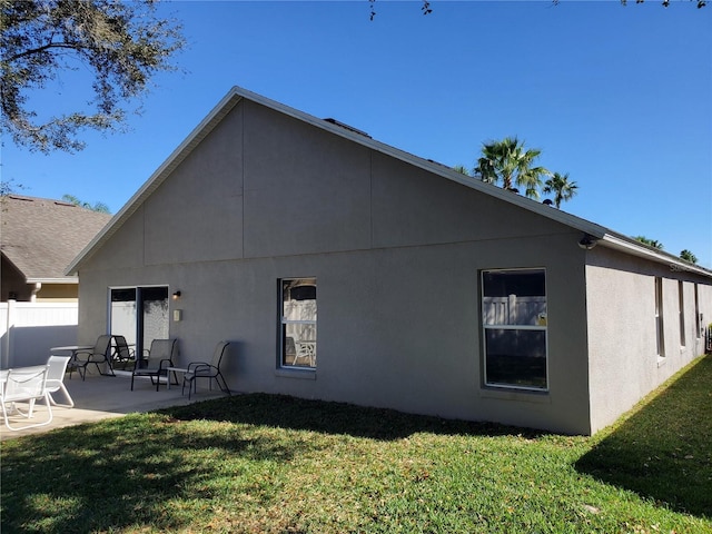 back of property with a patio, a lawn, fence, and stucco siding