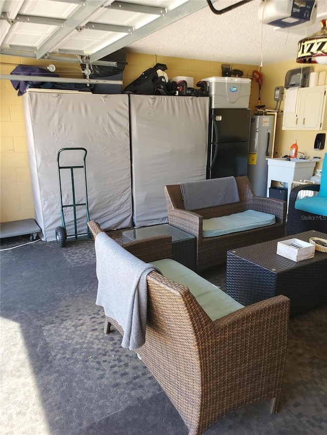 garage featuring concrete block wall, a garage door opener, water heater, and freestanding refrigerator