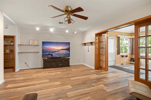 unfurnished living room featuring visible vents, a textured ceiling, a ceiling fan, and wood finished floors