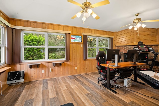 office area featuring wooden walls, heating unit, wood finished floors, and ceiling fan