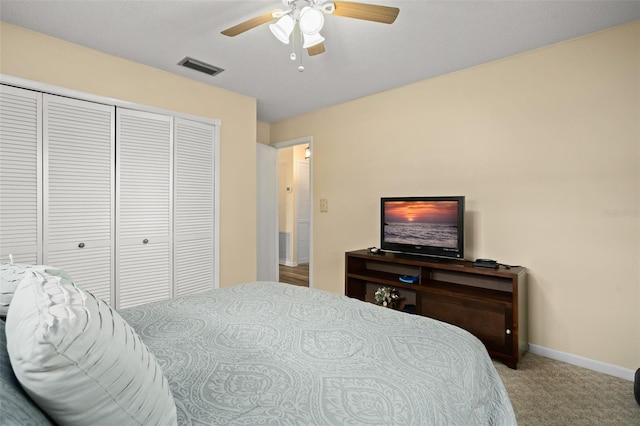 carpeted bedroom with visible vents, baseboards, a closet, and ceiling fan